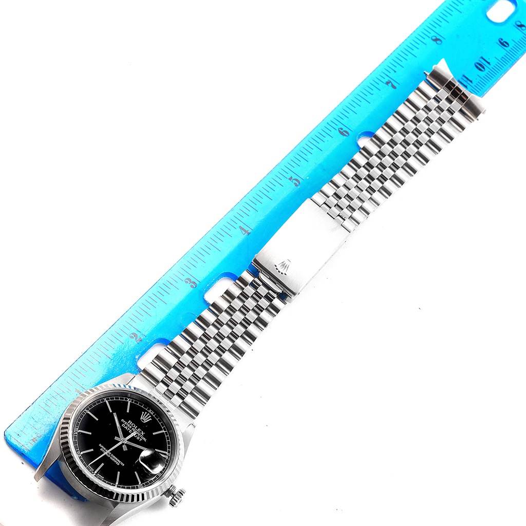 The image shows the entire Rolex Datejust 16234 Men's Stainless Steel Black Dial 16234 Men's Stainless Steel Black Dial watch laid flat alongside a ruler, displaying the face, bezel, and bracelet.