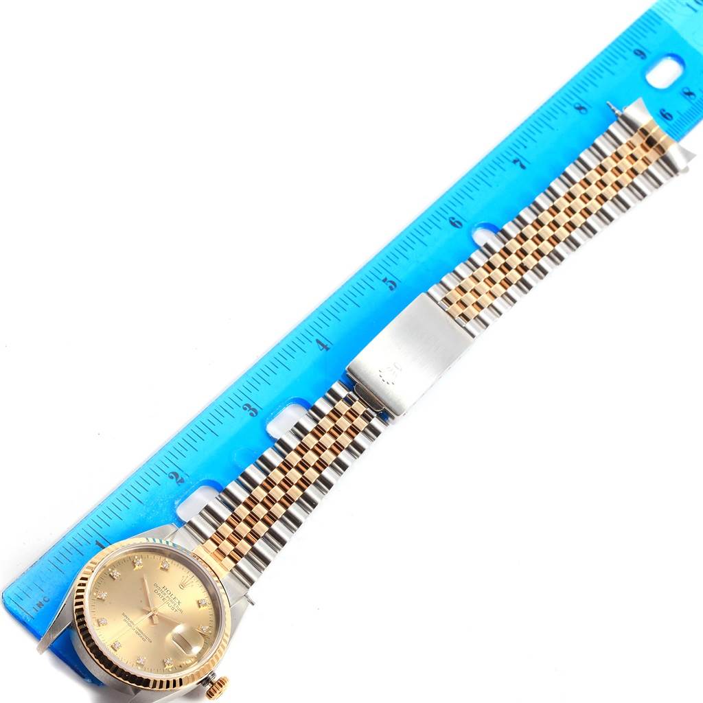 The image shows a Rolex Datejust 16233 Men's Steel and Gold (two tone) Champagne Dial 16233 Men's Steel and Gold (two tone) Champagne Dial watch laid flat next to a blue ruler, displaying the face and band.