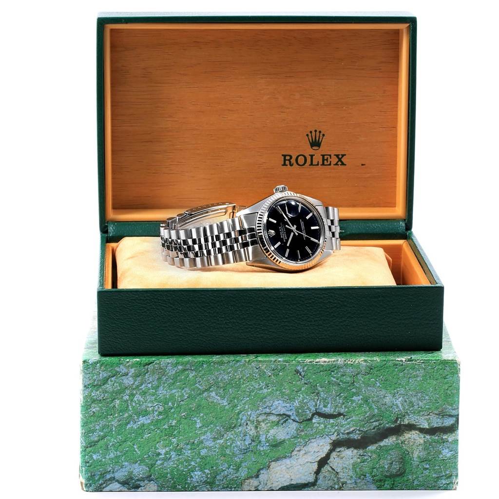 The Rolex Datejust 1601 Men's Stainless Steel Black Dial 1601 Men's Stainless Steel Black Dial watch is shown from a front angle, resting in an open green and wood box.