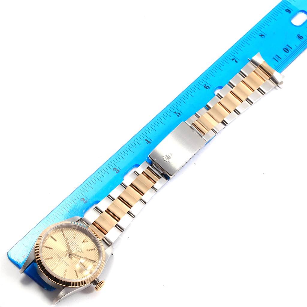 The image shows a full view of a Rolex Datejust 16233 Men's Steel and Gold (two tone) Champagne Dial 16233 Men's Steel and Gold (two tone) Champagne Dial watch and its bracelet placed next to a blue ruler for scale.