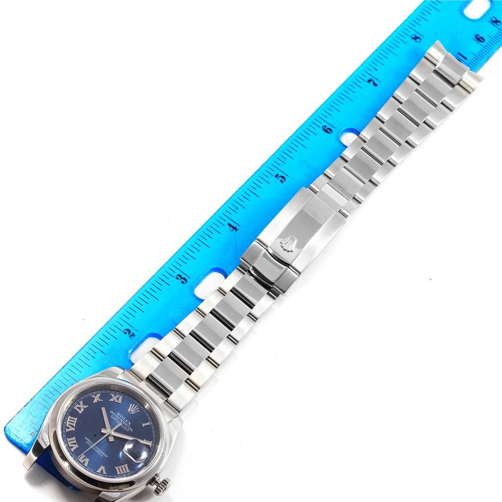 The image shows a Rolex Datejust 116200 Men's Stainless Steel Blue Dial 116200 Men's Stainless Steel Blue Dial watch laid flat next to a blue ruler, displaying its band and clasp.
