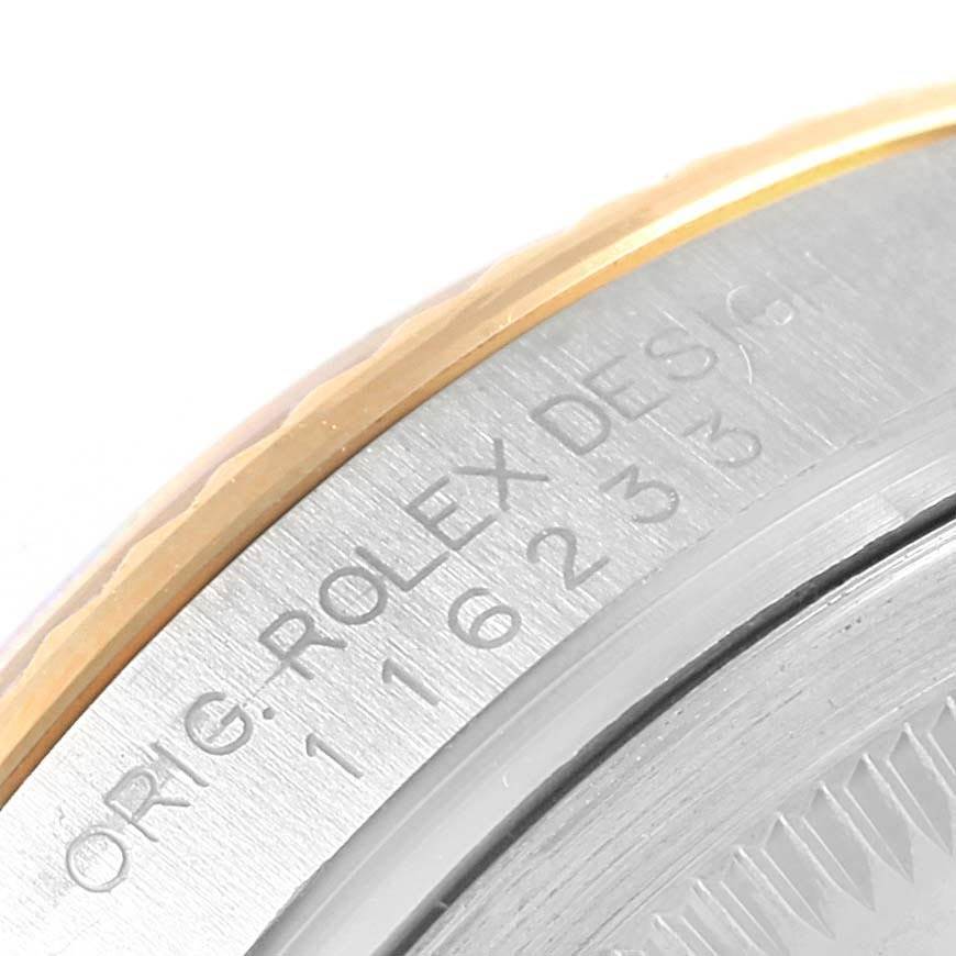 The image shows a close-up of the side with inscription and edge of the bezel of a Rolex Datejust 116233 Men's Stainless Steel Champagne Dial 116233 Men's Stainless Steel Champagne Dial watch.
