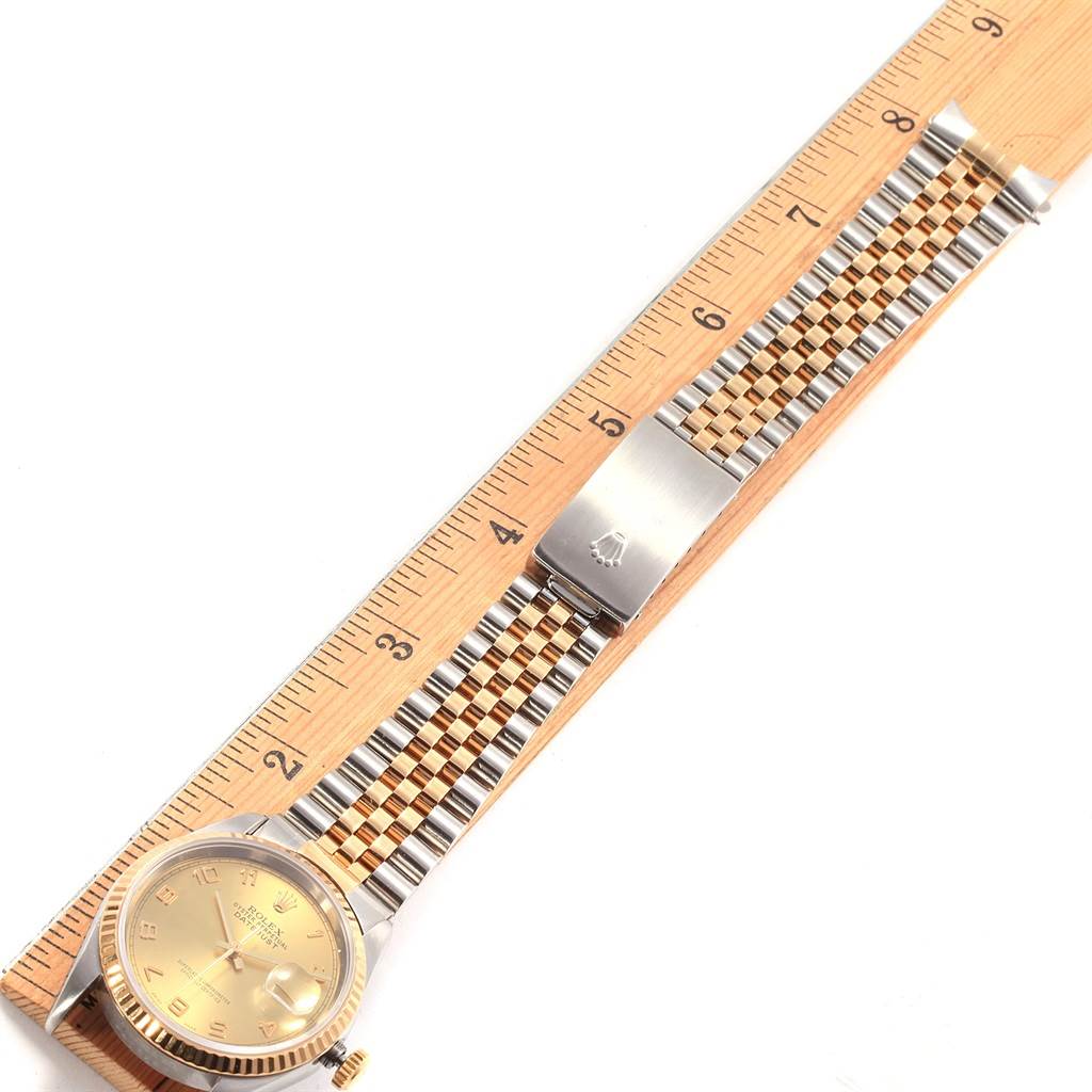 The Rolex Datejust 16233 Men's Steel and Gold (two tone) Champagne Dial 16233 Men's Steel and Gold (two tone) Champagne Dial watch is shown lying flat with the dial face, bracelet, and clasp visible, next to a ruler for scale.