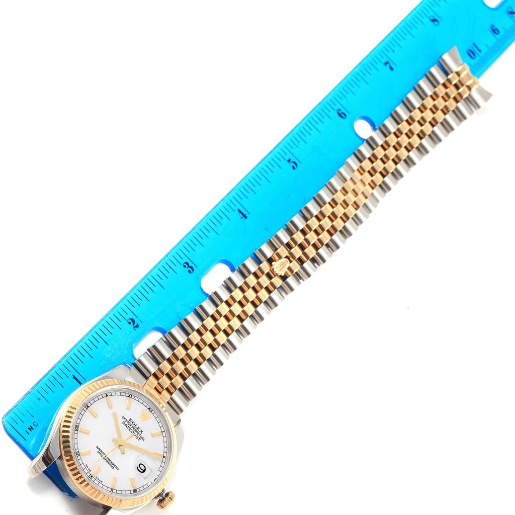 The image shows a Rolex Datejust 116233 Men's Stainless Steel White Dial 116233 Men's Stainless Steel White Dial watch with a two-tone bracelet, placed next to a blue ruler for measurement.