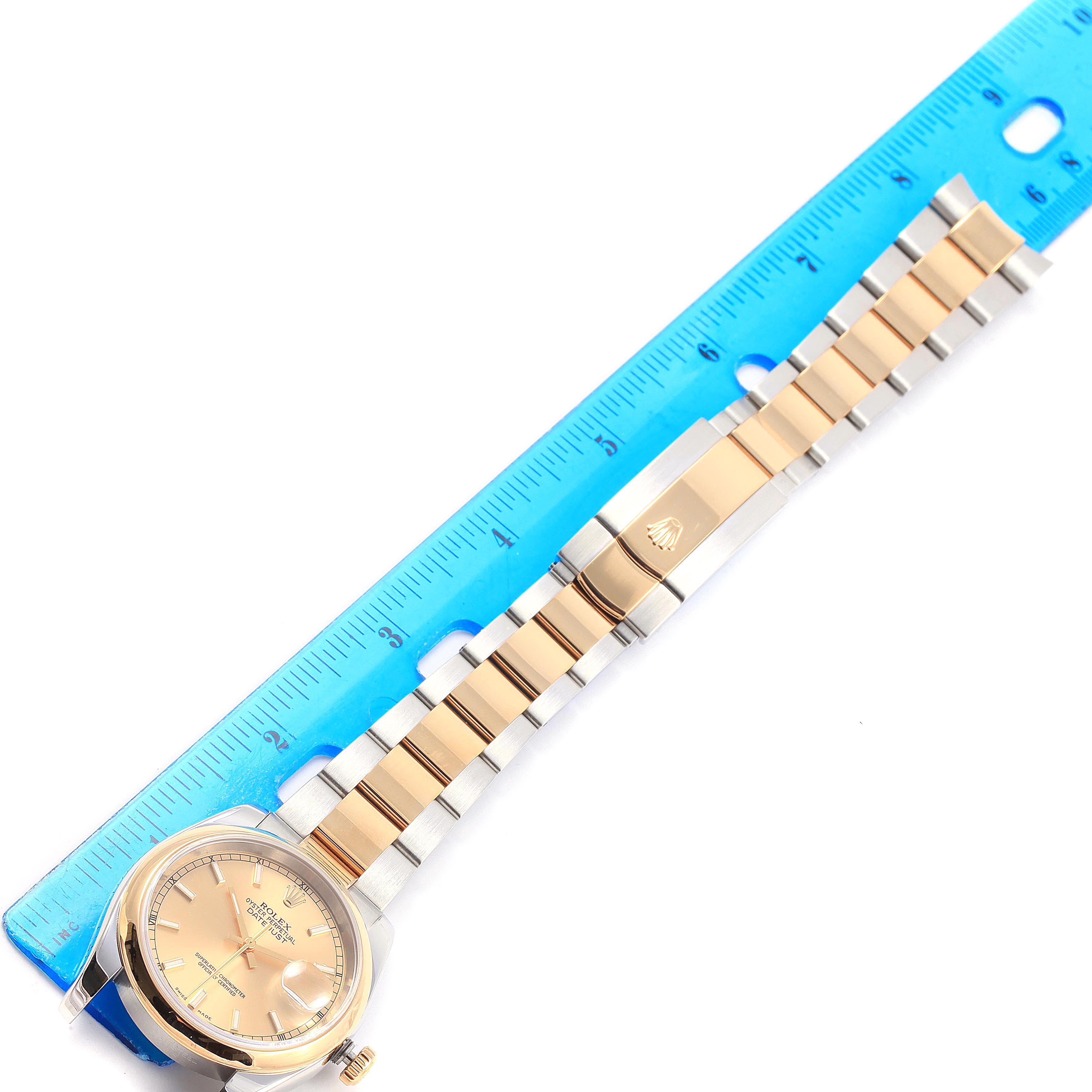 The image shows a Rolex Datejust 116203 Men's Stainless Steel Champagne Dial 116203 Men's Stainless Steel Champagne Dial watch laid flat next to a ruler, displaying its face, bracelet, and clasp.