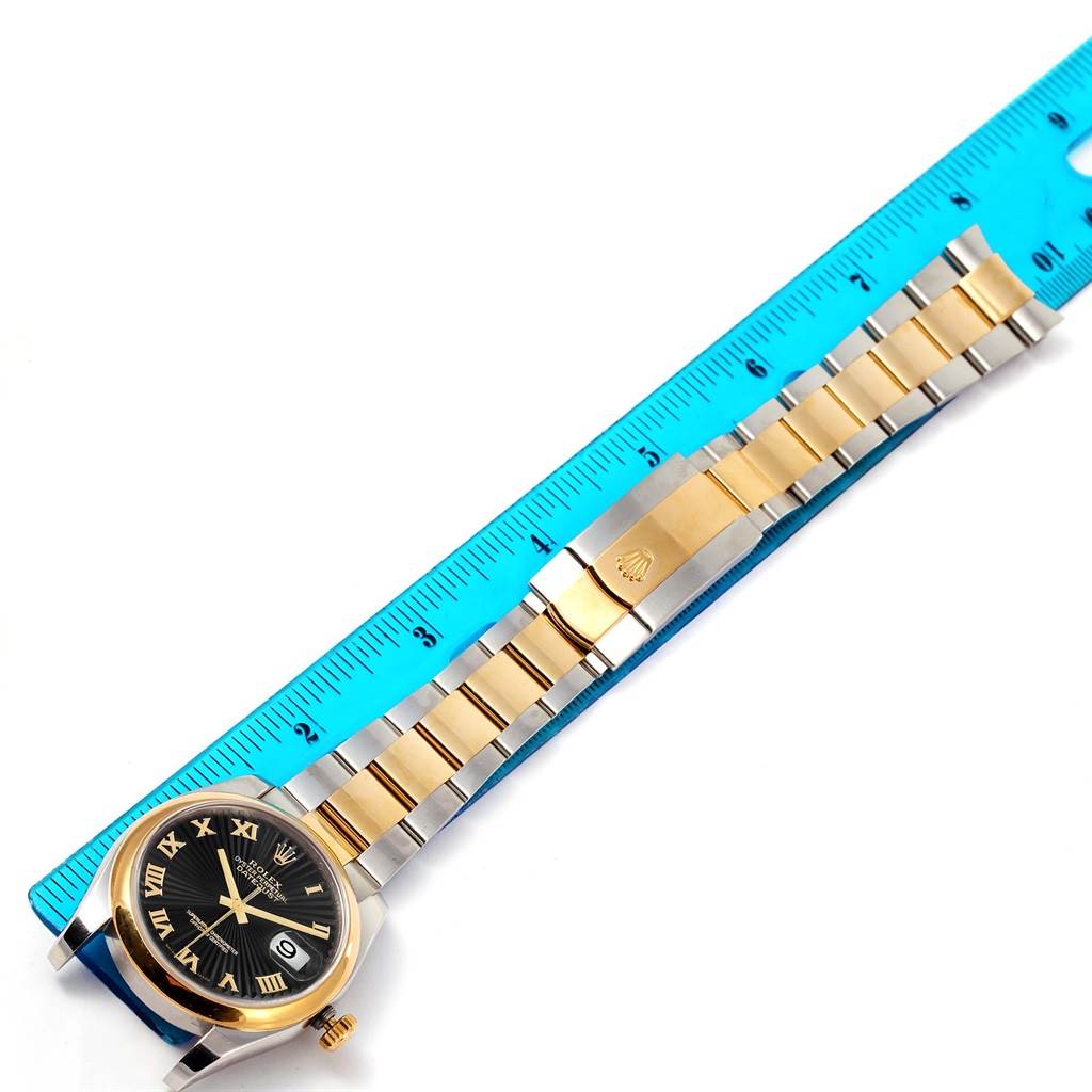 The Rolex Datejust 116203 Men
s Stainless Steel Black Dial 116203 Men
s Stainless Steel Black Dial watch is shown laid flat next to a ruler, displaying the full bracelet and the face at an overhead view.
