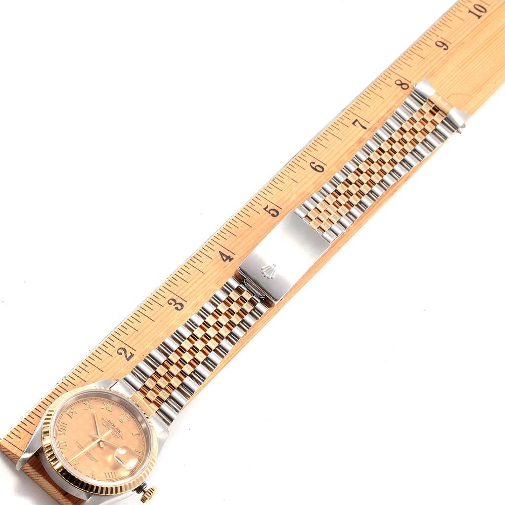 The Rolex Datejust 16233 Men's Steel and Gold (two tone) Beige Dial 16233 Men's Steel and Gold (two tone) Beige Dial watch is shown from the top view, displaying its face, crown, and full bracelet alongside a wooden ruler for scale.