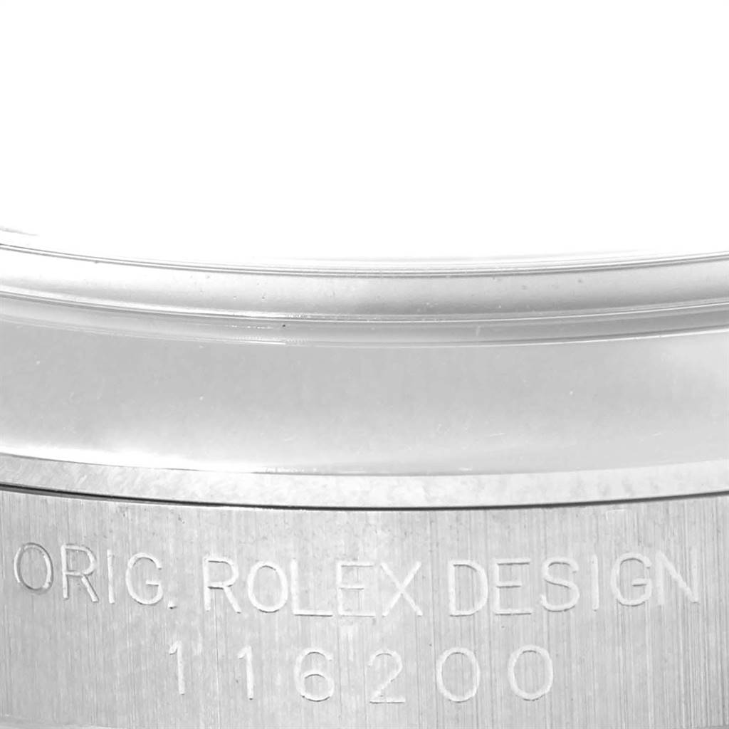 The image shows a close-up view of the engraved side of the case of a Rolex Datejust 116200 Men's Stainless Steel Silver Dial 116200 Men's Stainless Steel Silver Dial watch.