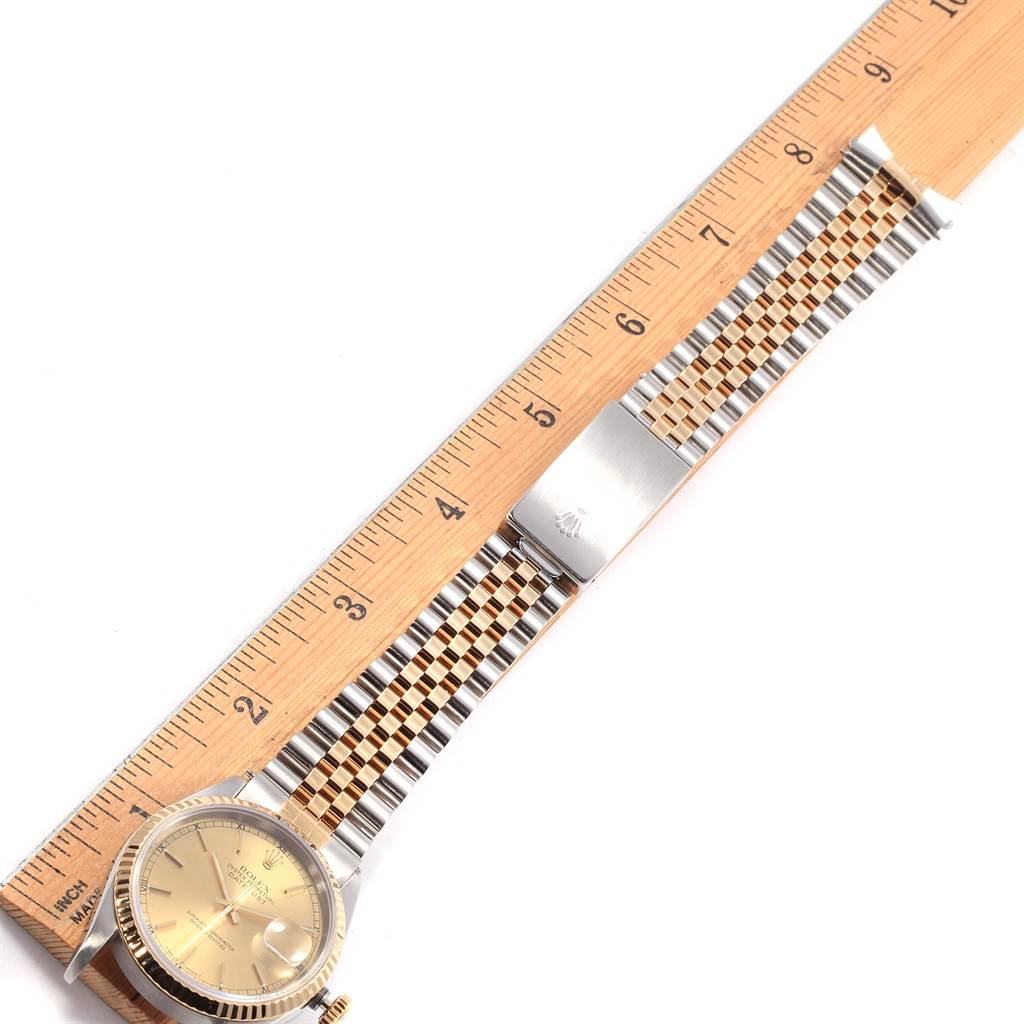The Rolex Datejust 16233 Men's Steel and Gold (two tone) Champagne Dial 16233 Men's Steel and Gold (two tone) Champagne Dial watch is shown in a top view, with the face, crown, and bracelet stretched next to a ruler for measurement.