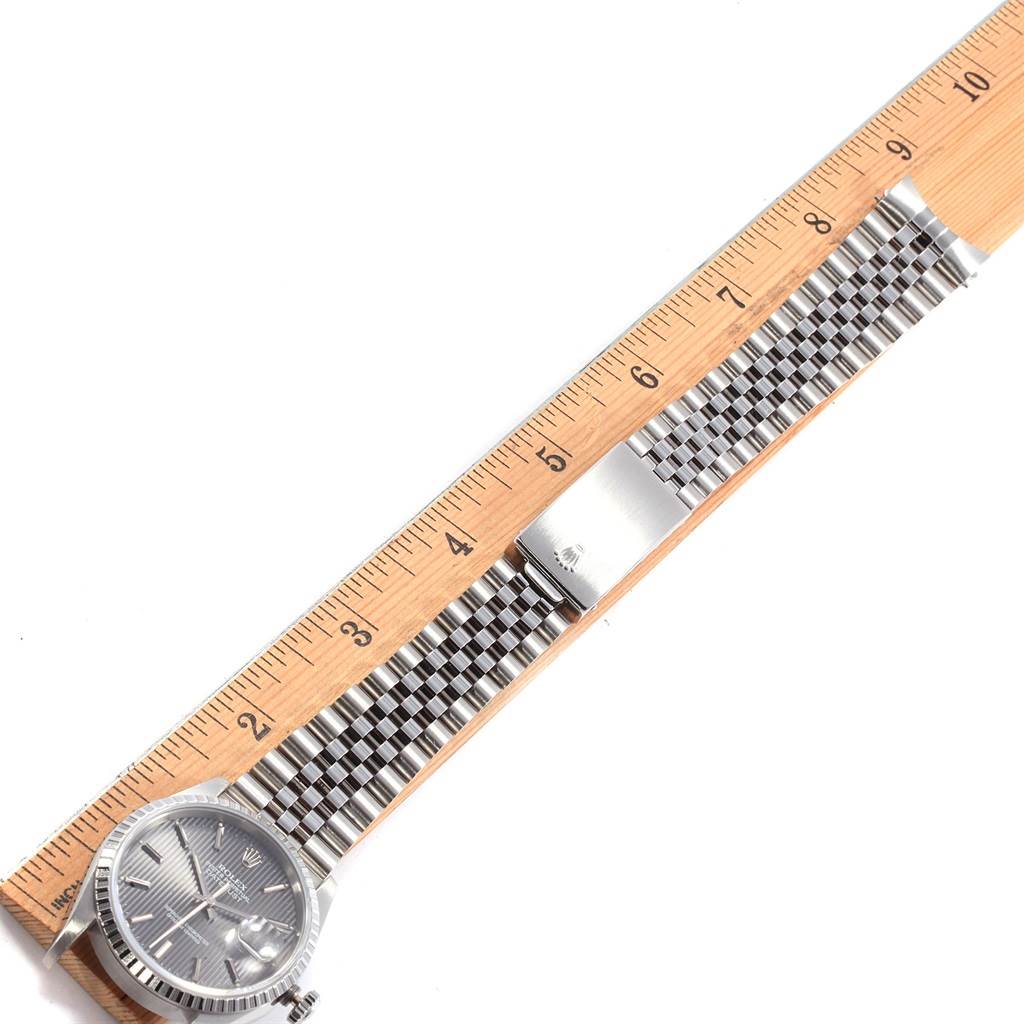 The Rolex Datejust 16220 Men's Stainless Steel Grey Dial 16220 Men's Stainless Steel Grey Dial watch is shown from a top-down angle with its bracelet fully laid out next to a ruler.