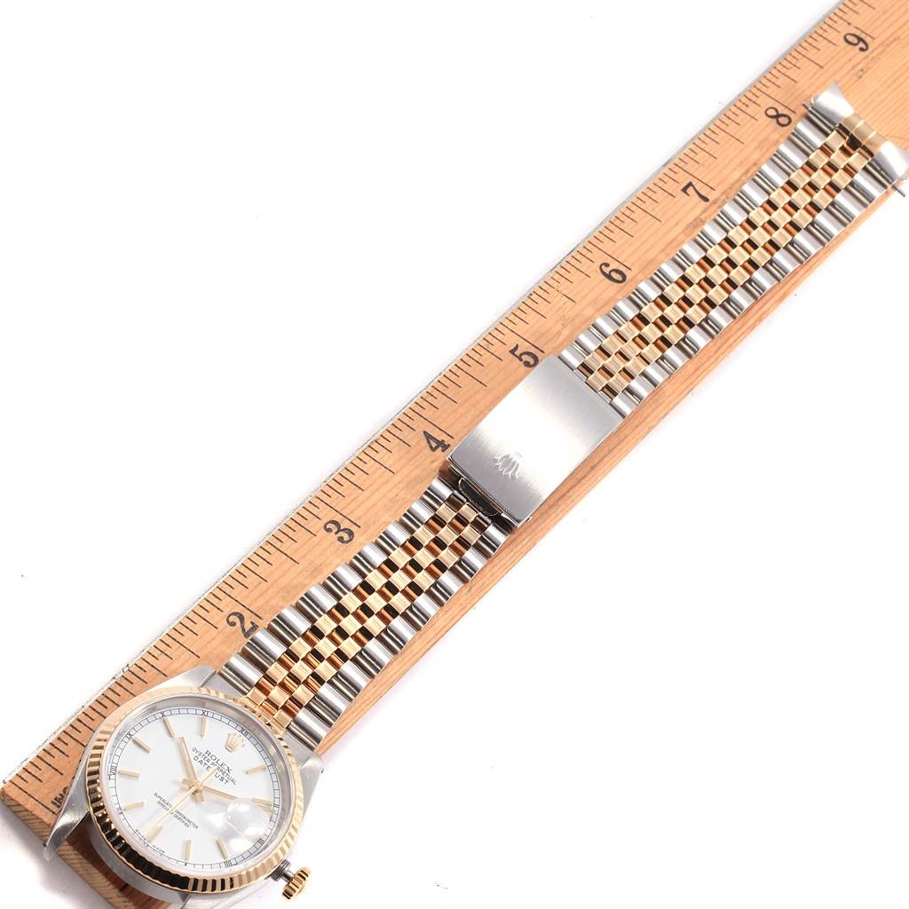 This image shows a Rolex Datejust 16233 Men
s Steel and Gold (two tone) White Dial 16233 Men
s Steel and Gold (two tone) White Dial watch, detailing part of the dial, bezel, and bracelet alongside a ruler for measurement.