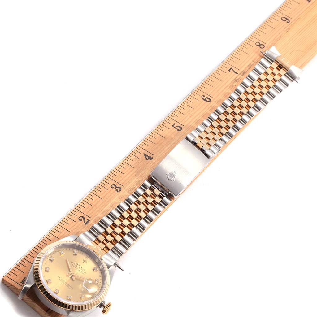 The Datejust Rolex watch shown is laid flat alongside a ruler, displaying the face, bracelet, and clasp.