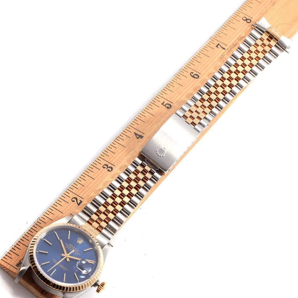 The Rolex Datejust 16233 Men's Steel and Gold (two tone) Blue Dial 16233 Men's Steel and Gold (two tone) Blue Dial watch is shown from a top-down angle, displaying its face, bracelet, and clasp next to a ruler.