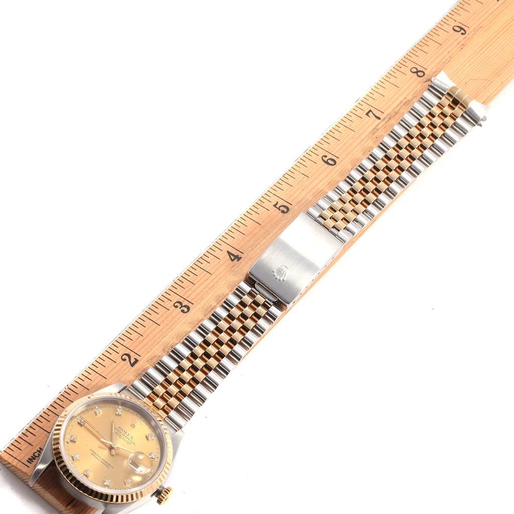 The Rolex Datejust 16233 Men's Steel and Gold (two tone) Champagne Dial 16233 Men's Steel and Gold (two tone) Champagne Dial watch is shown laid flat with a ruler, displaying its face, bracelet, and clasp.