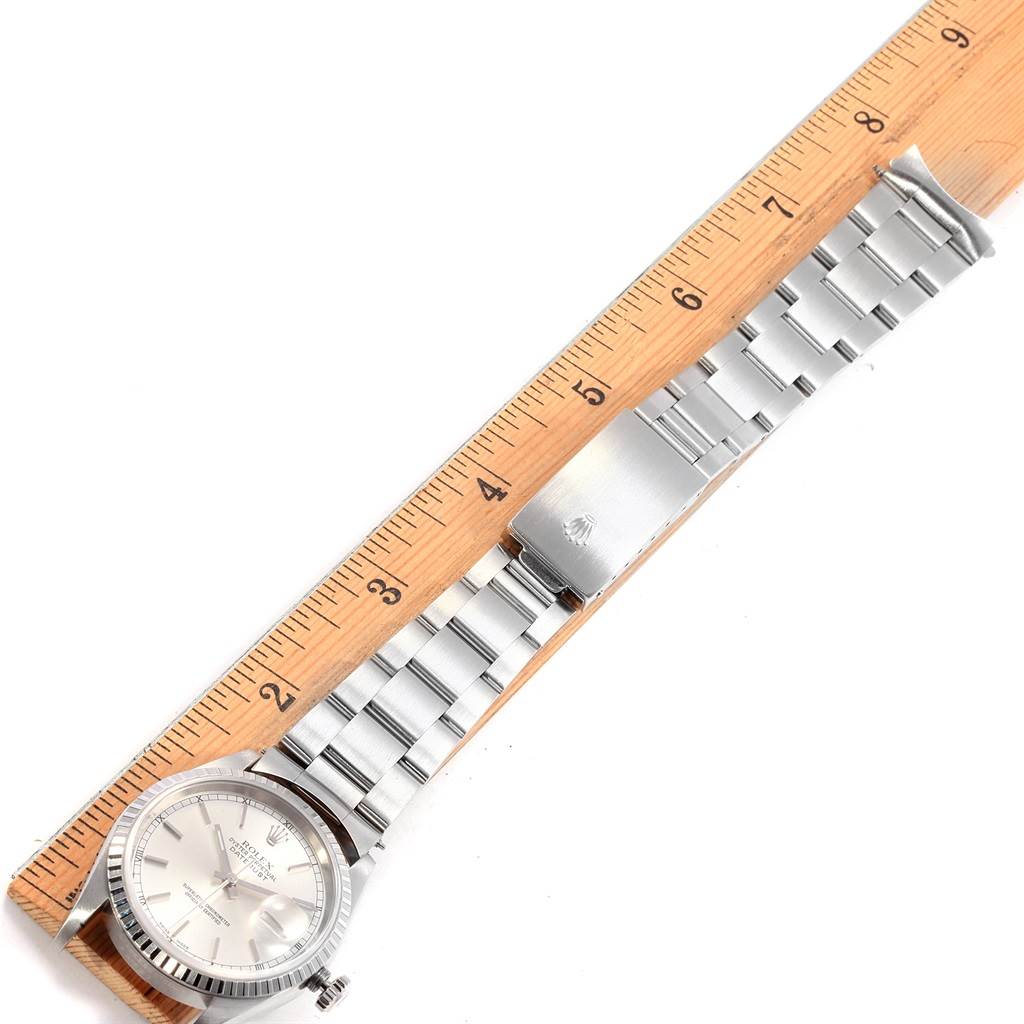 The Rolex Datejust 16220 Men's Stainless Steel Silver Dial 16220 Men's Stainless Steel Silver Dial watch is displayed flat on a ruler, showcasing its face, bezel, and full bracelet length.