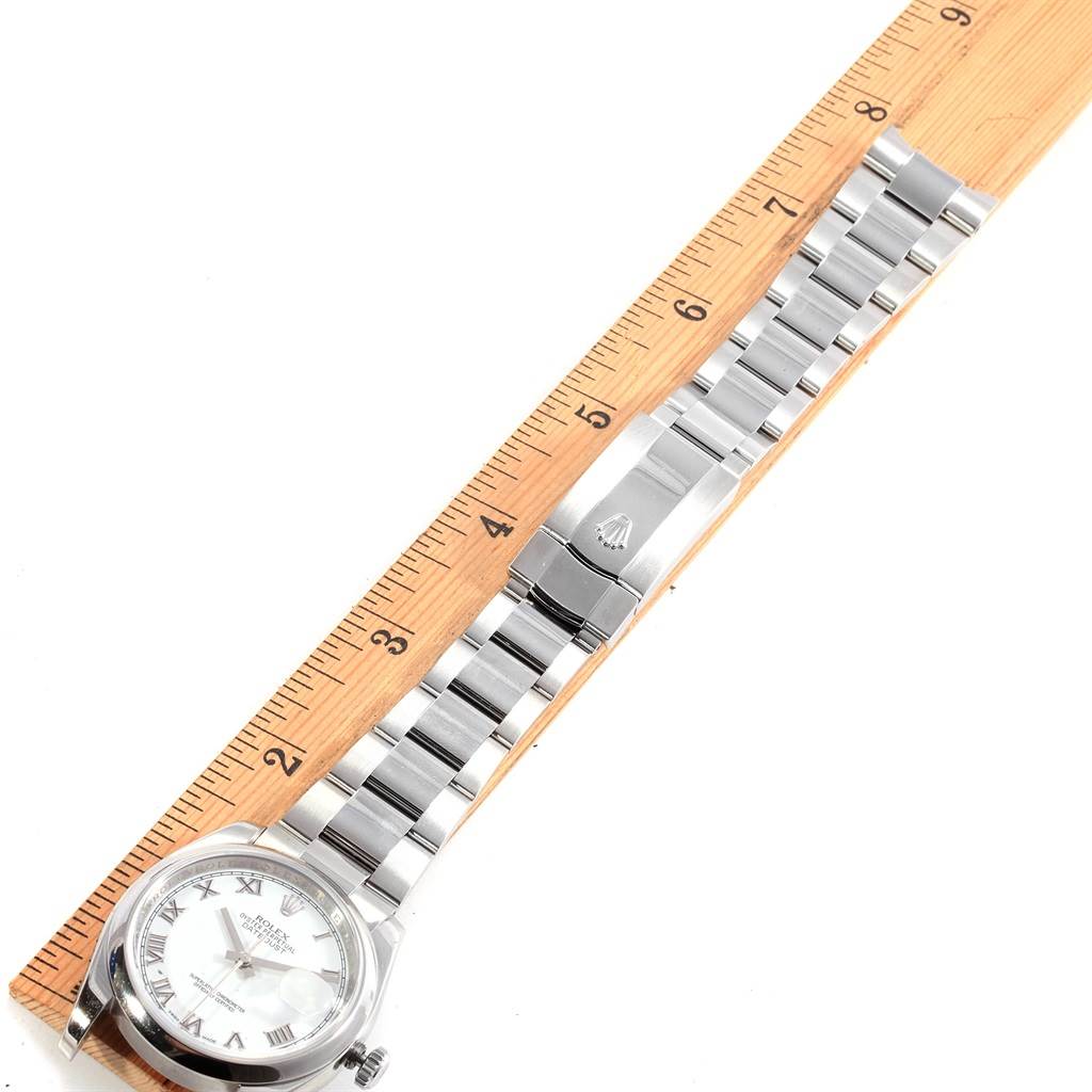 The Rolex Datejust 116200 Men's Stainless Steel White Dial 116200 Men's Stainless Steel White Dial watch is shown from a top-down angle, displaying the face, bracelet, and clasp, against a ruler for scale.