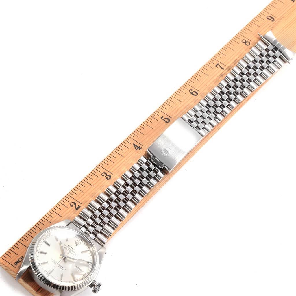 The Rolex Datejust 16014 Men's Stainless Steel Silver Dial 16014 Men's Stainless Steel Silver Dial watch is shown from a top-down angle, displaying the face, bezel, and full bracelet laid next to a ruler.