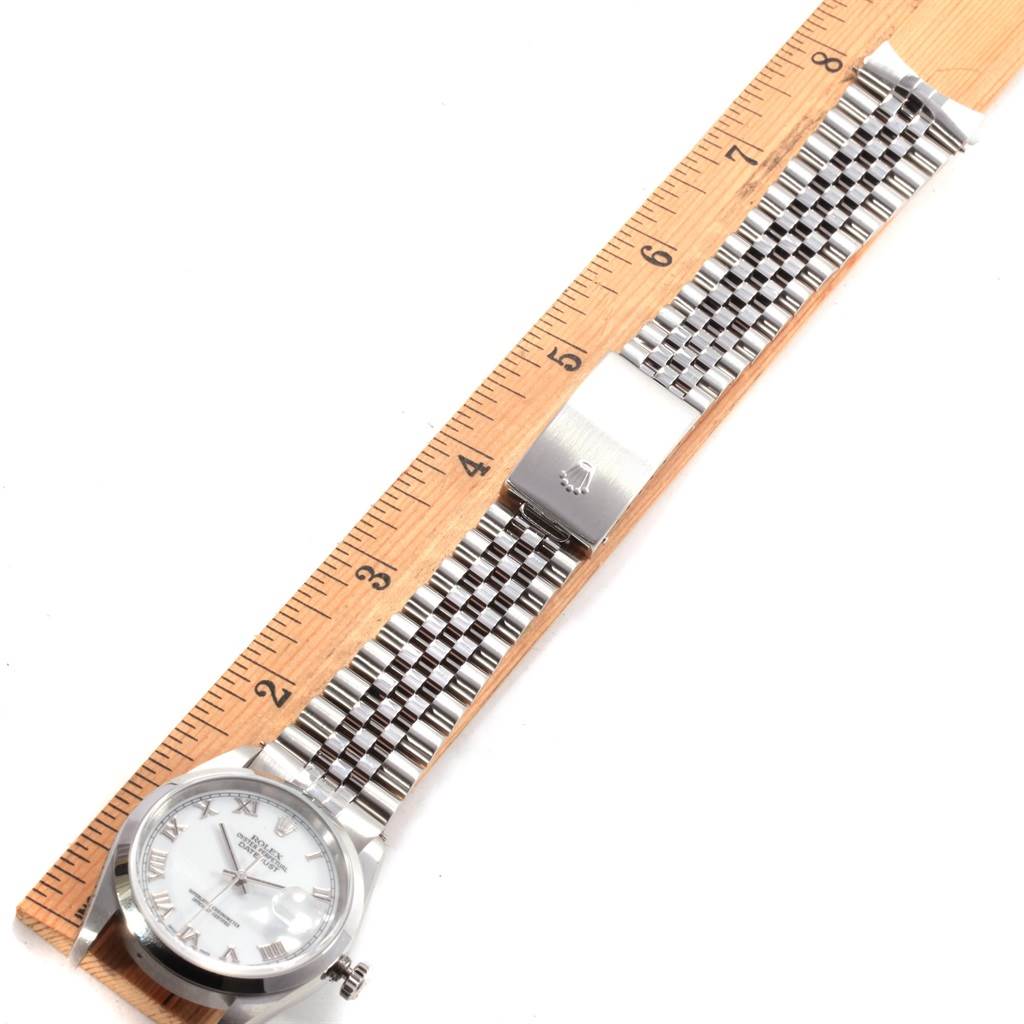 The Rolex Datejust 16200 Men
s Stainless Steel White Dial 16200 Men
s Stainless Steel White Dial model watch is shown from a top-down angle, displaying the watch face, bracelet, and clasp next to a ruler.