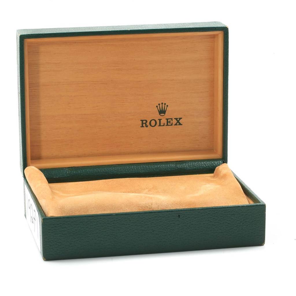 The image shows an open green and wood Rolex box, likely for a Datejust model watch, with a beige cushion inside.