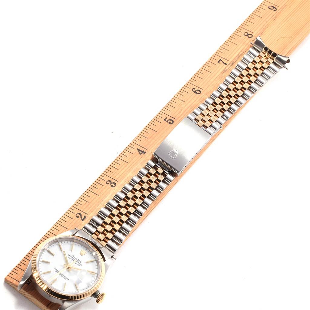 This image shows a Rolex Datejust 16233 Men
s Steel and Gold (two tone) White Dial 16233 Men
s Steel and Gold (two tone) White Dial watch placed alongside a ruler, highlighting its face, bezel, and two-tone bracelet.