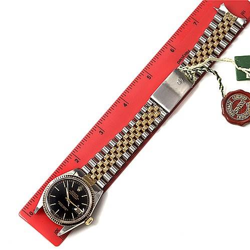 The Rolex Datejust 16013 Men
s Stainless Steel Black Dial 16013 Men
s Stainless Steel Black Dial watch is shown from a top-down angle, featuring its face, bracelet, clasp, and attached tags.