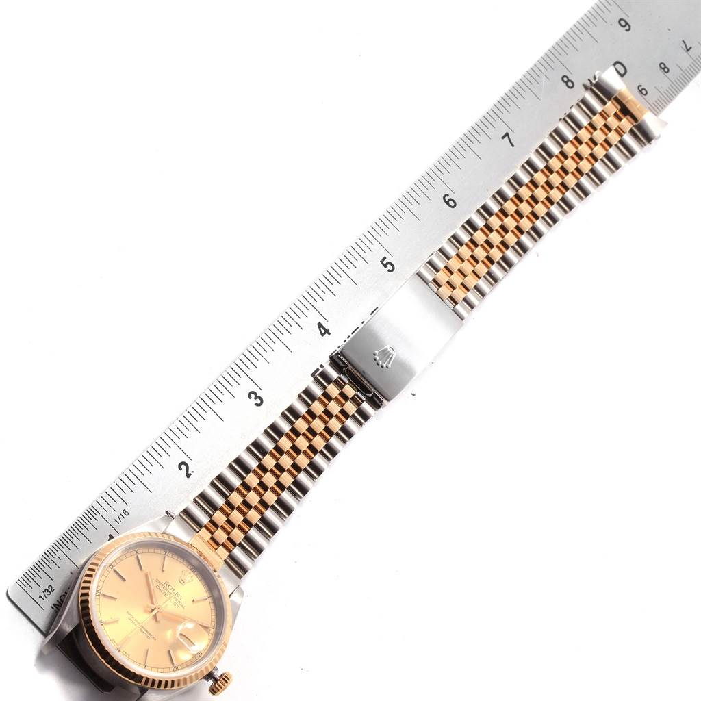 The image shows a flat lay of a Rolex Datejust 16233 Men's Steel and Gold (two tone) Champagne Dial 16233 Men's Steel and Gold (two tone) Champagne Dial watch, displaying its face, bezel, and two-tone bracelet next to a ruler.