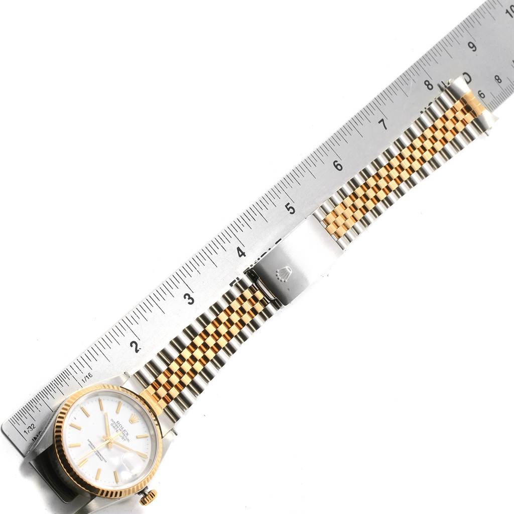 The Rolex Datejust 16233 Men's Steel and Gold (two tone) White Dial 16233 Men's Steel and Gold (two tone) White Dial watch is shown from above, highlighting its face, two-tone bracelet, and deployment clasp, alongside a ruler for scale.