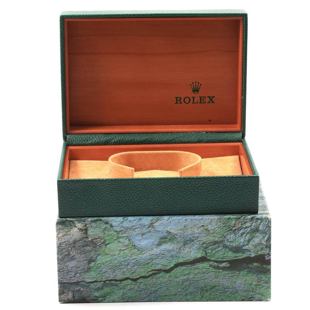 The image shows an open Rolex Datejust 16220 Men
s Stainless Steel Black Dial 16220 Men
s Stainless Steel Black Dial watch box with a green exterior and a velvet cushion inside.