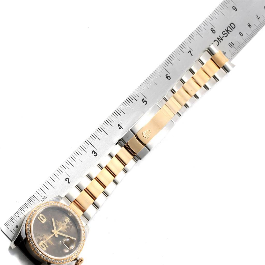The image shows a Rolex Datejust 116243 Men
s Stainless Steel Brown Dial 116243 Men
s Stainless Steel Brown Dial watch laid flat against a ruler, highlighting its face, bezel, bracelet, and clasp.