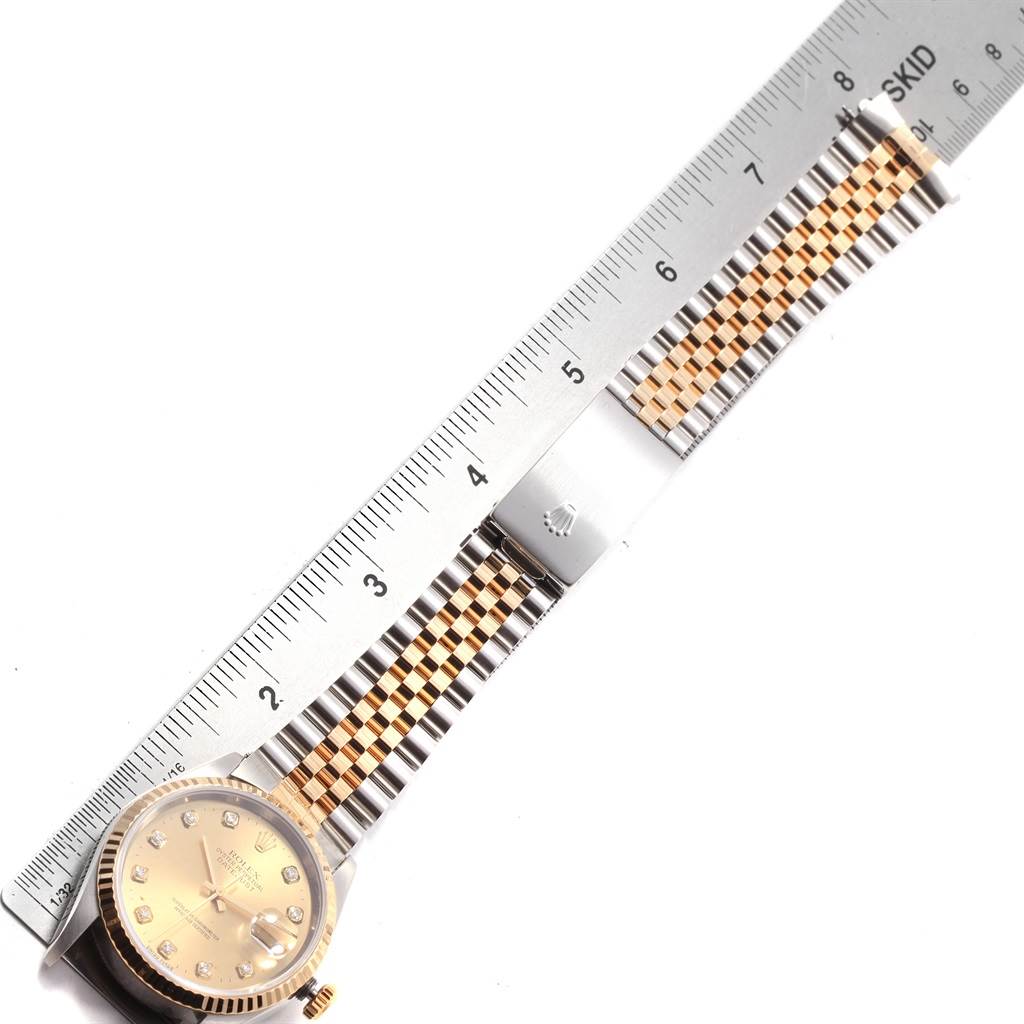 This image shows a Rolex Datejust 16233 Men's Steel and Gold (two tone) Champagne Dial 16233 Men's Steel and Gold (two tone) Champagne Dial watch laid flat with a ruler for scale, highlighting its dial and two-tone bracelet.
