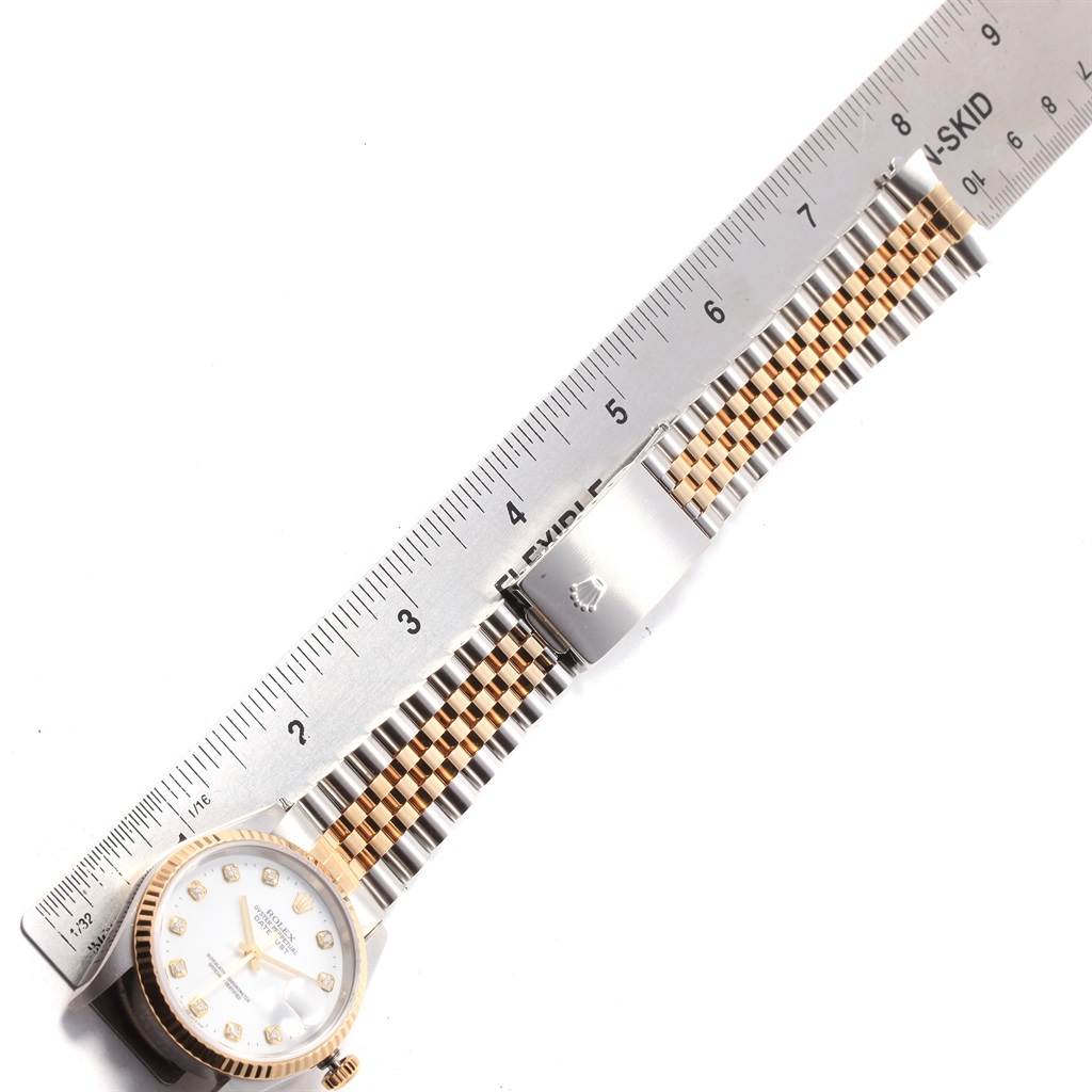 The Rolex Datejust 16233 Men's Steel and Gold (two tone) White Dial 16233 Men's Steel and Gold (two tone) White Dial watch is shown from an overhead angle, displaying the face, bezel, and two-tone bracelet beside a ruler.