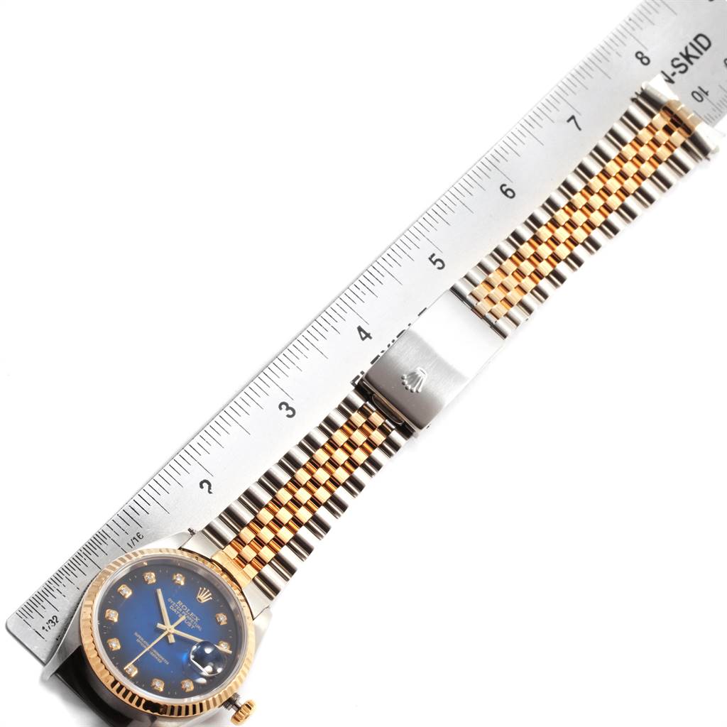 This image shows a Rolex Datejust 16233 Men's Steel and Gold (two tone) Blue Dial 16233 Men's Steel and Gold (two tone) Blue Dial watch with its blue dial and two-tone bracelet against a ruler for measurement.