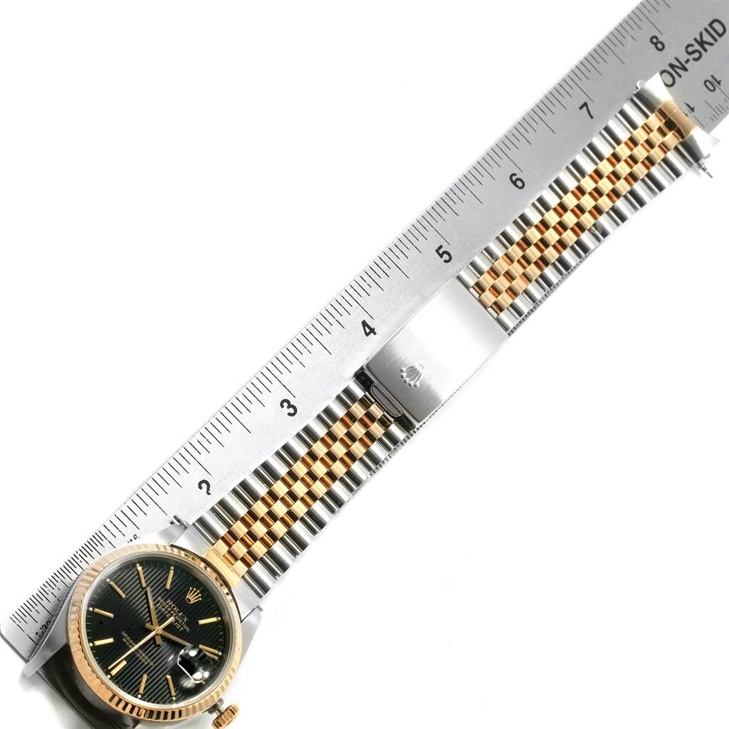 This image shows a Rolex Datejust 16233 Men's Steel and Gold (two tone) Black Dial 16233 Men's Steel and Gold (two tone) Black Dial watch laid flat under a ruler, highlighting the gold and silver bracelet and face from a top-down angle.