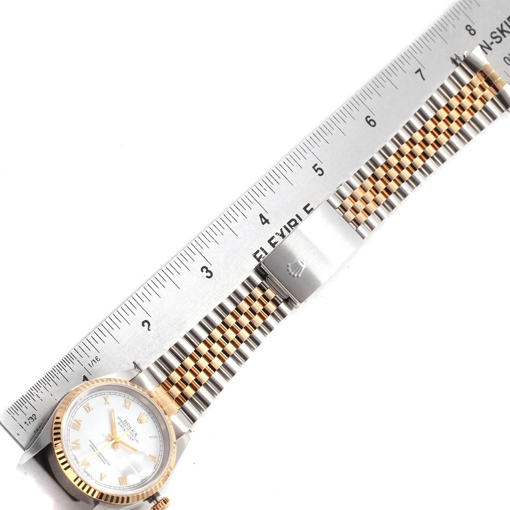 The image shows a Rolex Datejust 16233 Men's Steel and Gold (two tone) White Dial 16233 Men's Steel and Gold (two tone) White Dial watch laid flat next to a ruler, highlighting the watch's bezel and two-tone bracelet.