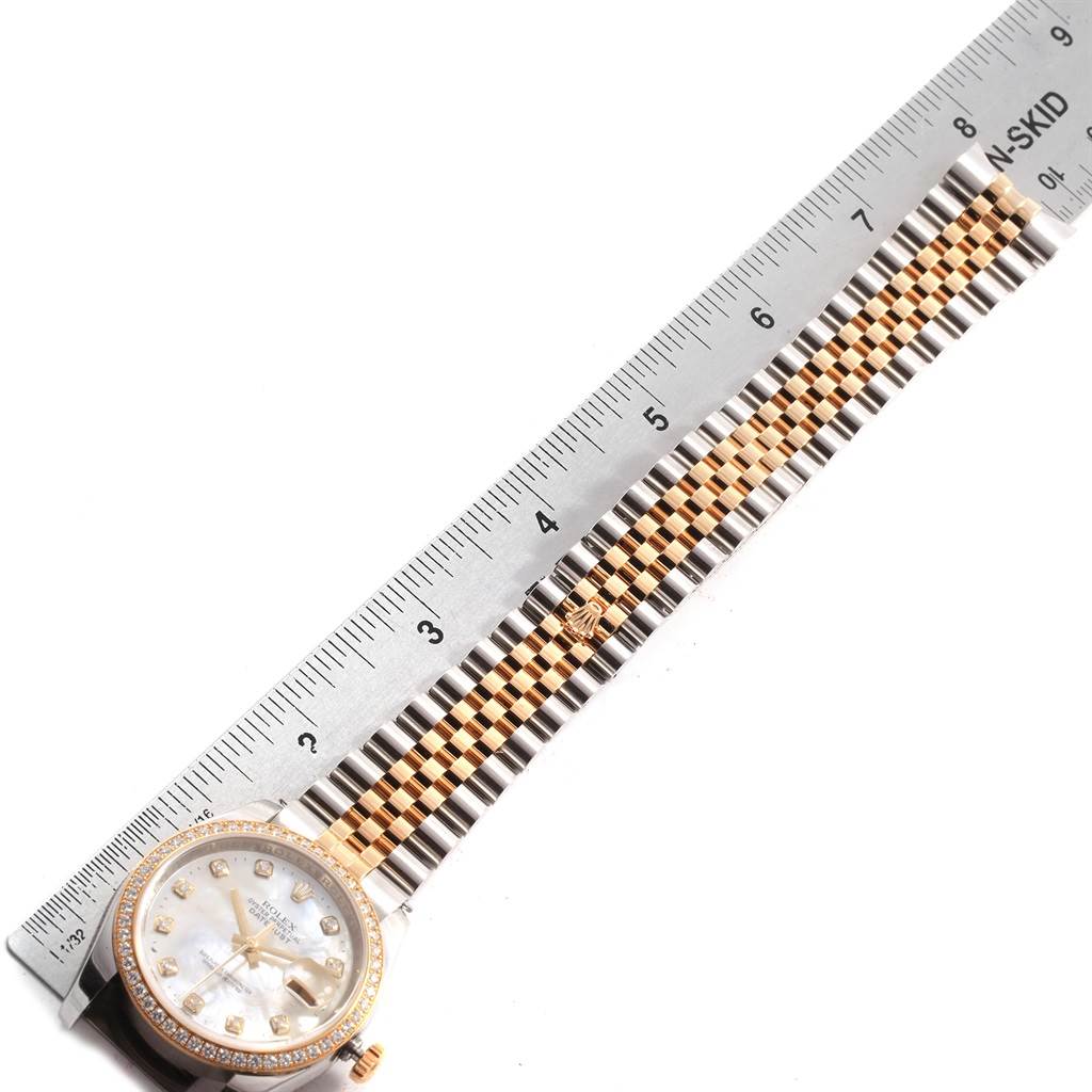 The image shows a Rolex Datejust 116243 Men's Stainless Steel Silver Dial 116243 Men's Stainless Steel Silver Dial watch lying flat, complemented by a metal ruler placed beside its band for measurement.