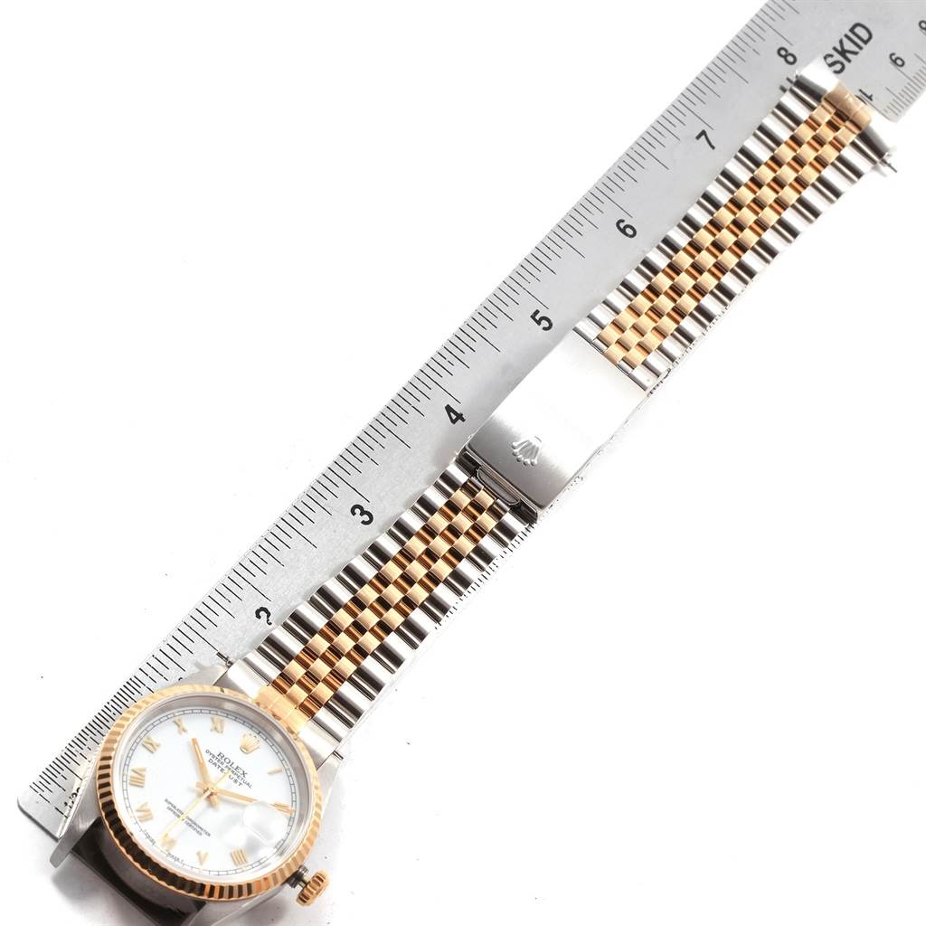 This image shows a Rolex Datejust 16233 Men
s Steel and Gold (two tone) White Dial 16233 Men
s Steel and Gold (two tone) White Dial watch in a top-down angle displaying the face, bezel, two-tone bracelet, and part of a metal ruler.