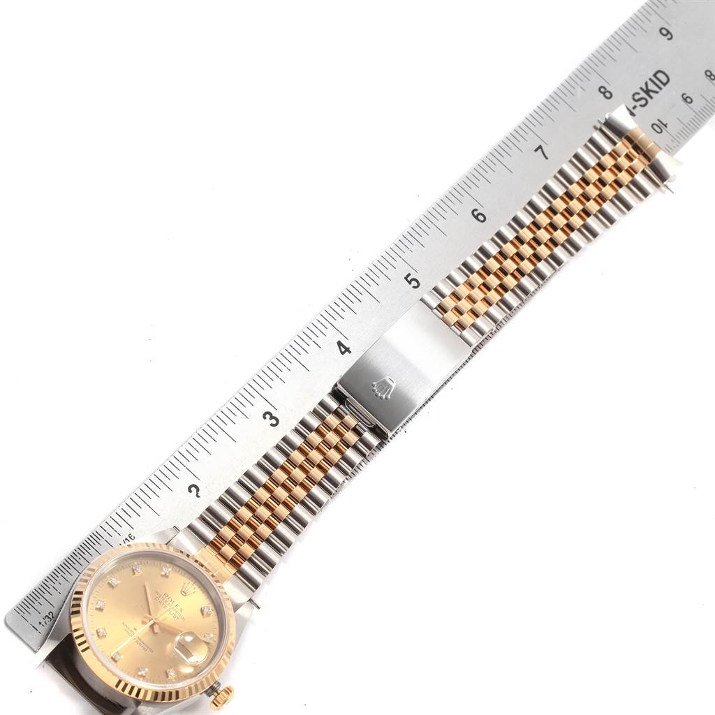 The image shows a Rolex Datejust 16233 Men
s Steel and Gold (two tone) Champagne Dial 16233 Men
s Steel and Gold (two tone) Champagne Dial watch laid flat next to a ruler, displaying the gold and silver band and face.