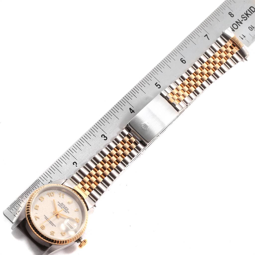 The Rolex Datejust 16233 Men
s Steel and Gold (two tone) Beige Dial 16233 Men
s Steel and Gold (two tone) Beige Dial watch is shown from an overhead angle, displaying the face and part of the metal bracelet along with a ruler.