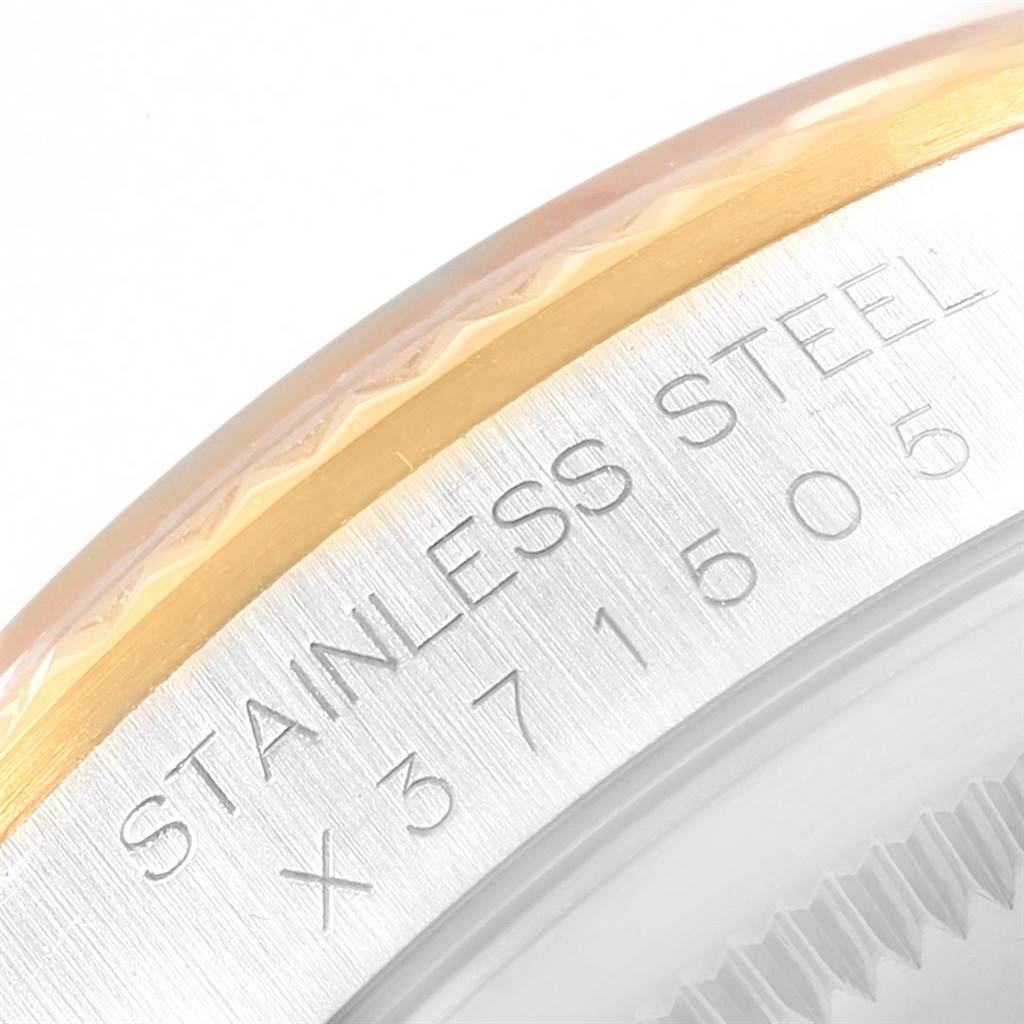 The image shows a close-up of the edge of a Rolex Datejust 16233 Men
s Steel and Gold (two tone) Champagne Dial 16233 Men
s Steel and Gold (two tone) Champagne Dial watch case with "STAINLESS STEEL" and serial number engraving.