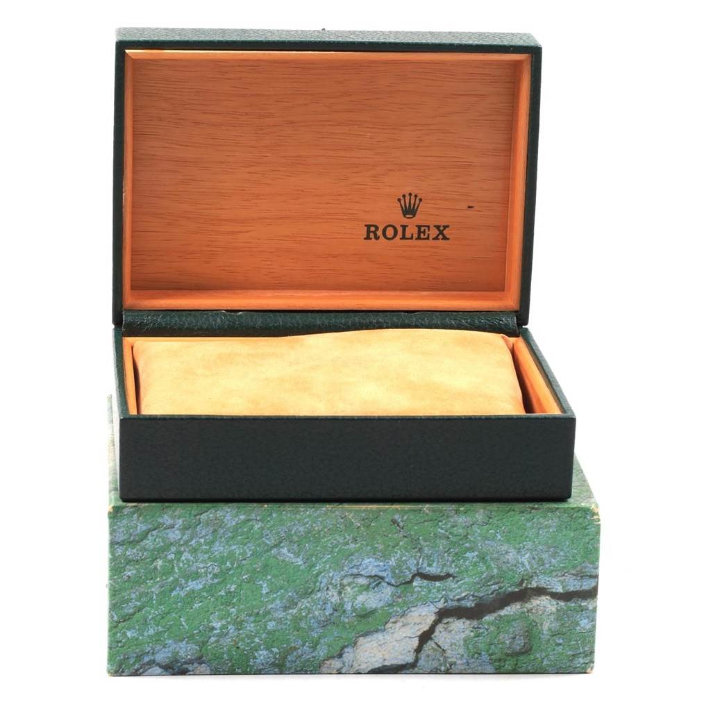 The image shows an open Rolex Datejust 16233 Men
s Steel and Gold (two tone) Champagne Dial 16233 Men
s Steel and Gold (two tone) Champagne Dial watch box, revealing a tan cushion inside the green and wood-finished case.