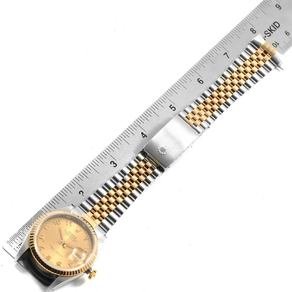 The image displays a Rolex Datejust 16233 Men
s Steel and Gold (two tone) Champagne Dial 16233 Men
s Steel and Gold (two tone) Champagne Dial watch laid flat alongside a ruler, showing its face and bracelet.