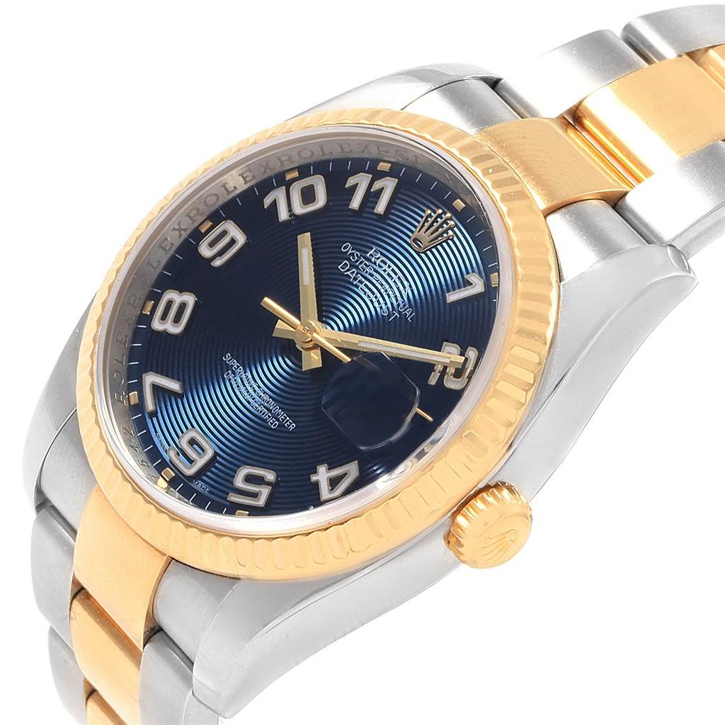 The image shows a Rolex Datejust 116233 Men
s Stainless Steel Blue Dial 116233 Men
s Stainless Steel Blue Dial watch at an angled view highlighting its blue dial, gold bezel, crown, and two-tone bracelet.
