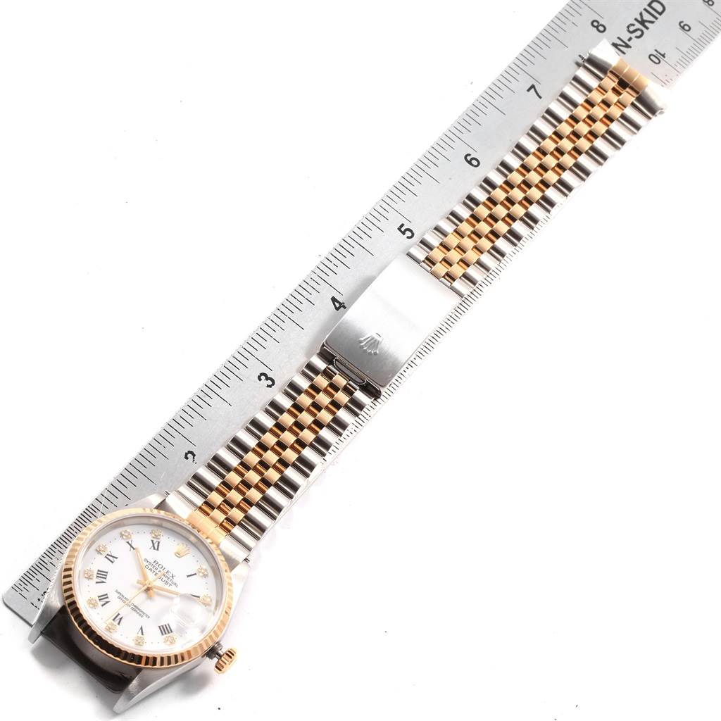 This image shows a top-down view of a Rolex Datejust 16233 Men's Steel and Gold (two tone) White Dial 16233 Men's Steel and Gold (two tone) White Dial watch, displaying its face, bezel, and two-tone bracelet against a ruler.