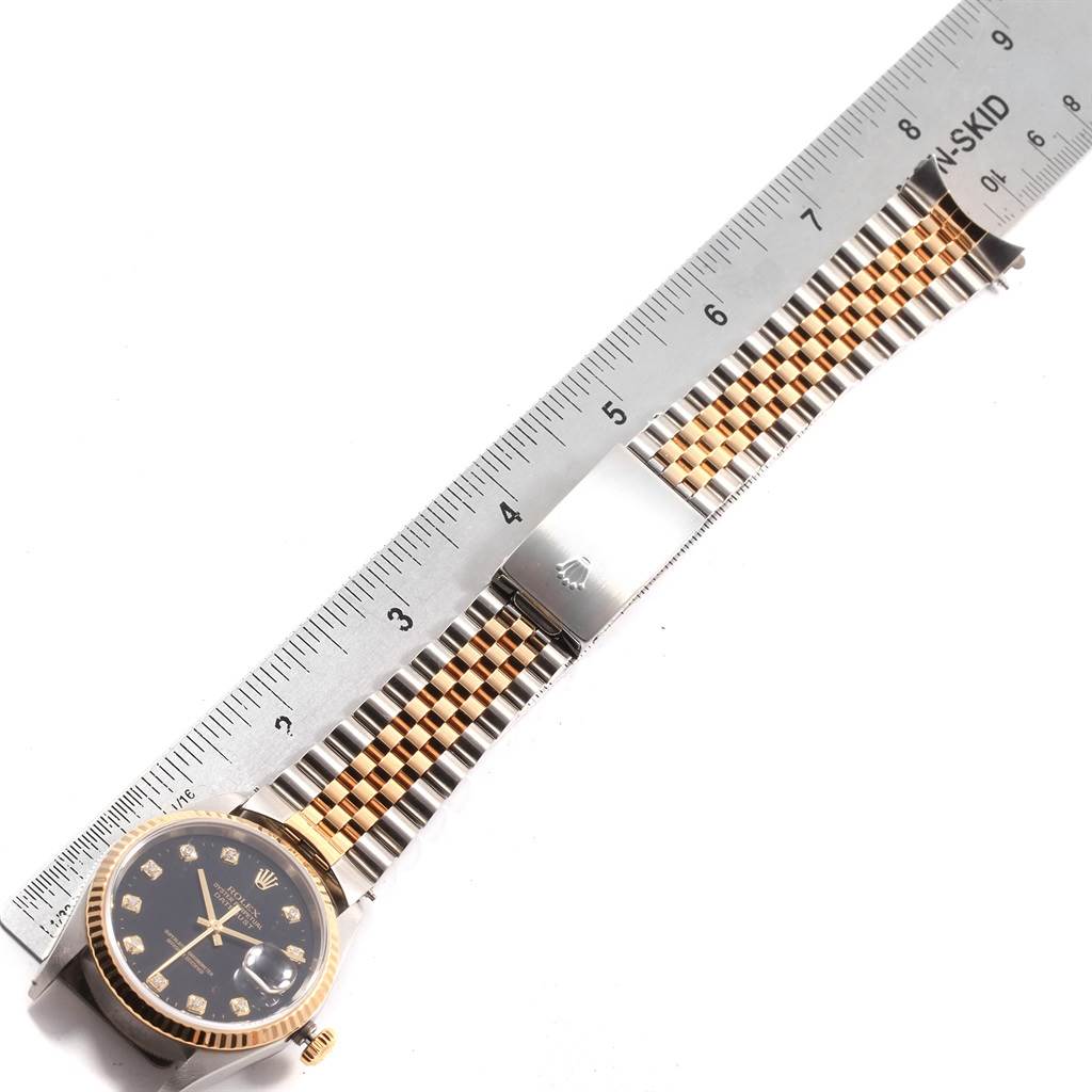 This image shows a side view of a Rolex Datejust 16233 Men
s Steel and Gold (two tone) Black Dial 16233 Men
s Steel and Gold (two tone) Black Dial watch with a ruler measuring its two-tone bracelet and clasp.