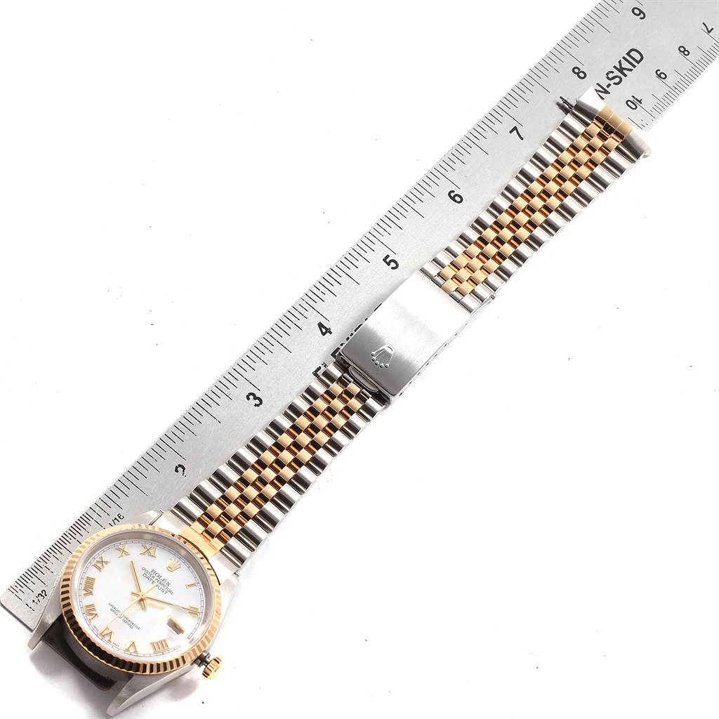 The Rolex Datejust 16233 Men's Steel and Gold (two tone) Mother of Pearl Dial 16233 Men's Steel and Gold (two tone) Mother of Pearl Dial watch is shown from a top-down angle, displaying its two-tone bracelet and dial alongside a ruler for scale.