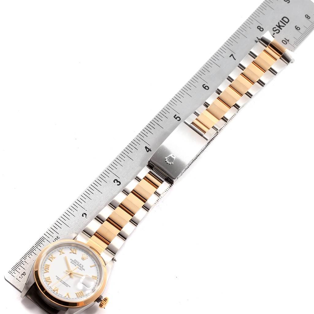 A Rolex Datejust 16203 Men's Steel and Gold (two tone) White Dial 16203 Men's Steel and Gold (two tone) White Dial watch is shown from an overhead angle, featuring the face, bracelet, and clasp, with a ruler for scale.