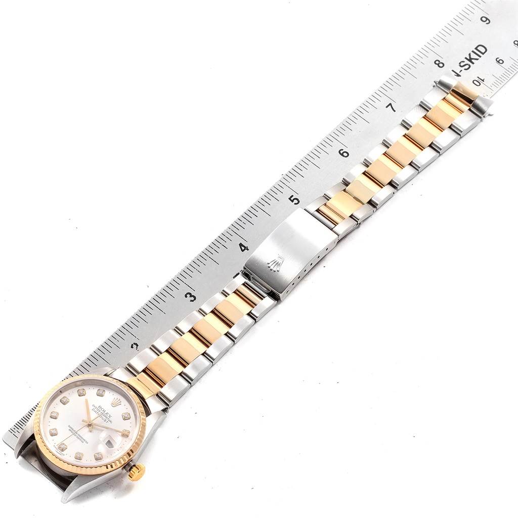 The Rolex Datejust 16233 Men's Steel and Gold (two tone) White Dial 16233 Men's Steel and Gold (two tone) White Dial watch is shown from a top-down angle with its full bracelet and a ruler for size reference.