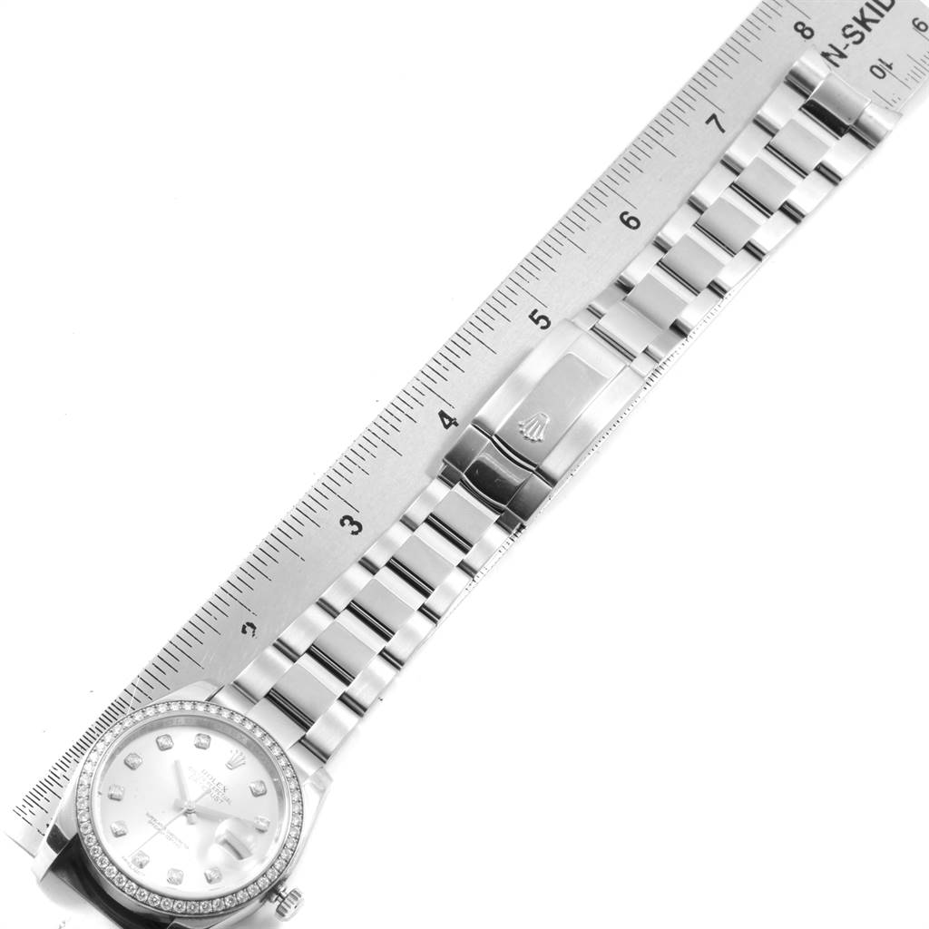 The image shows a Rolex Datejust 116244 Men
s Stainless Steel Silver Dial 116244 Men
s Stainless Steel Silver Dial watch laying flat with a ruler measuring the length of its bracelet.