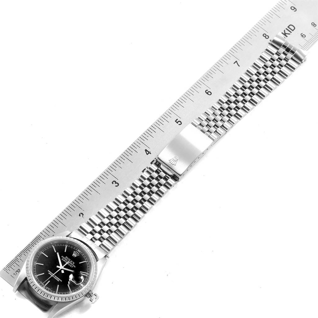 The image shows a Rolex Datejust 16220 Men
s Stainless Steel Black Dial 16220 Men
s Stainless Steel Black Dial watch lying flat with its face, bracelet, and clasp visible beside a ruler.