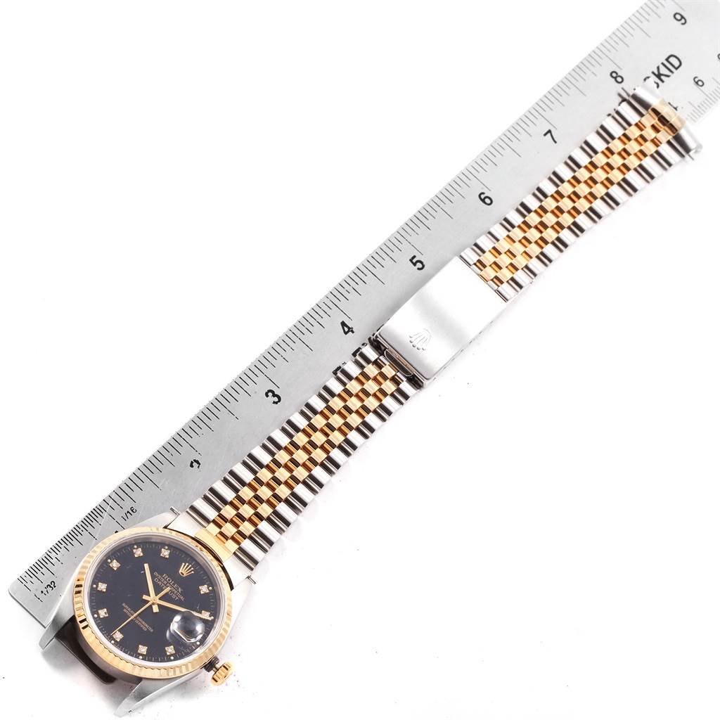 The image shows the Rolex Datejust 16233 Men
s Steel and Gold (two tone) Black Dial 16233 Men
s Steel and Gold (two tone) Black Dial watch laid flat with its jubilee bracelet extended alongside a ruler for measurement.